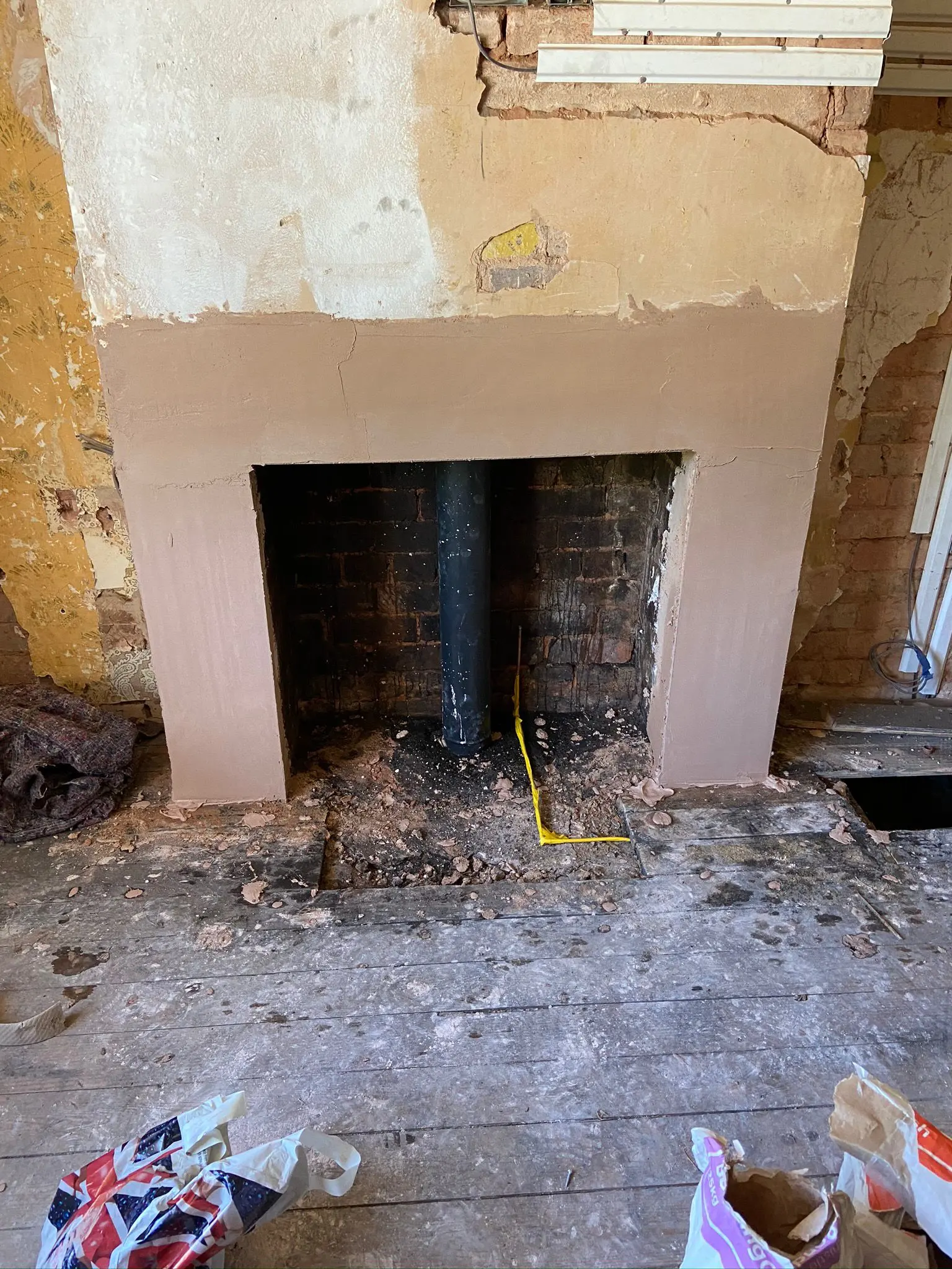 A fireplace renovation in progress with a flue pipe and gas safety tape installed by Gas Safe engineers.