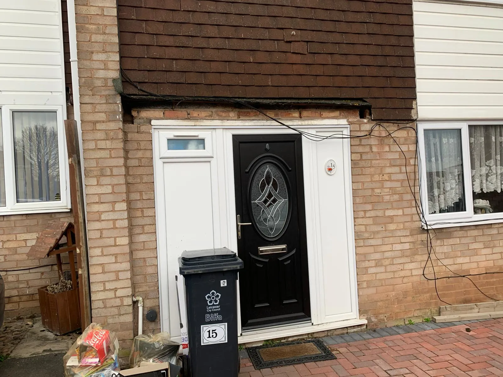 Damaged tile hanging and loose wires above a house front door in Gloucestershire
