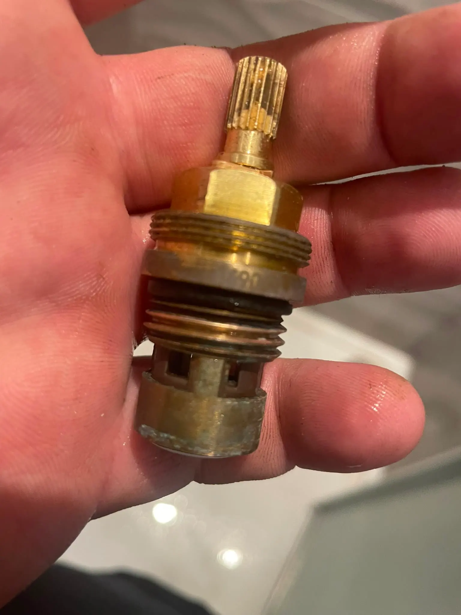A close up of a brass tap valve held in a plumber's hand