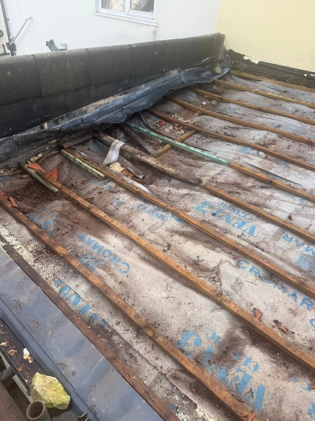 Professional roof replacement in progress showing exposed battens and membrane