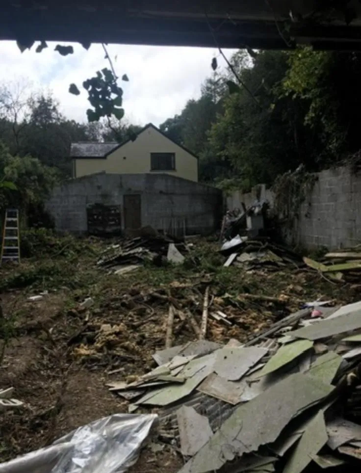 Site clearance of a demolished asbestos garage showing debris and broken asbestos cement sheets.