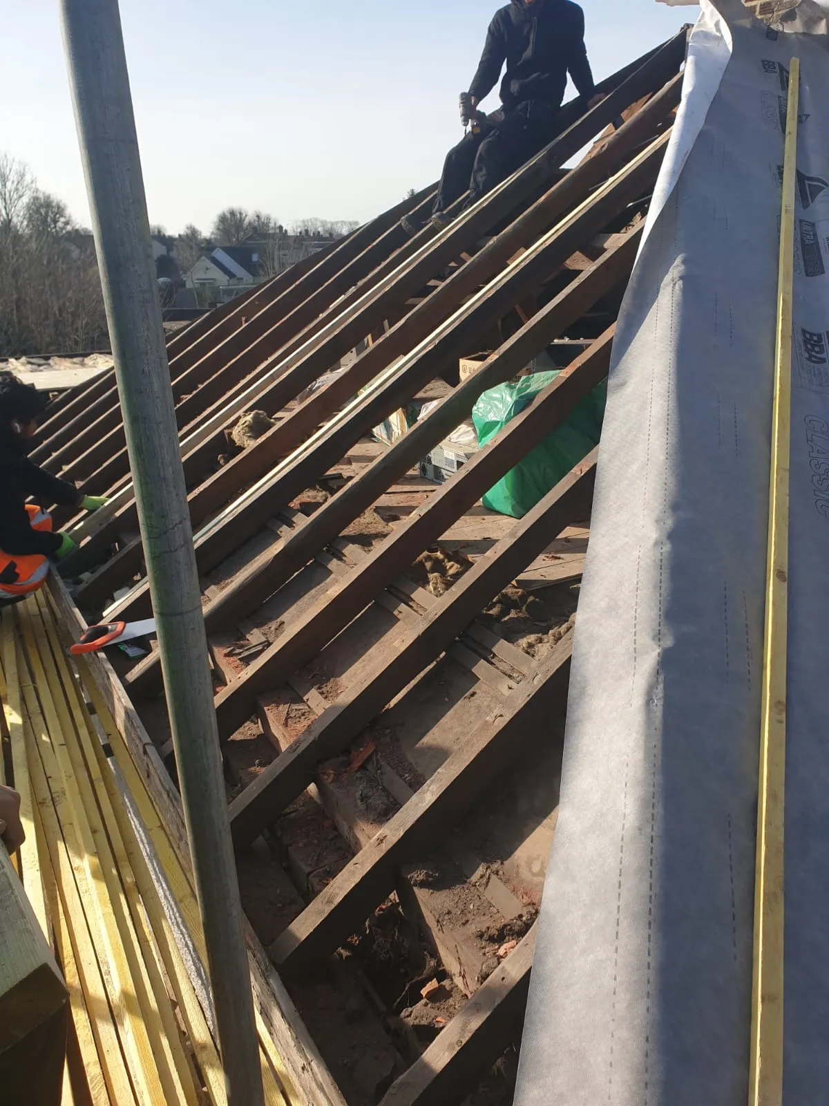 Roofers working on a timber roof frame for a re-roofing project in Cornwall