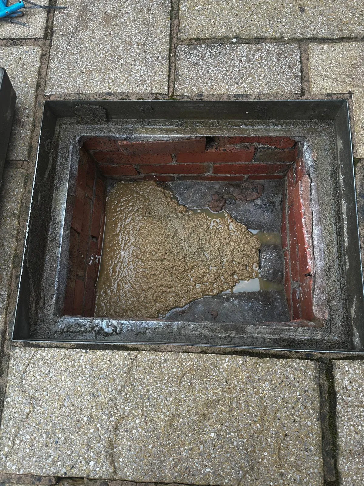 A severely blocked outdoor drain or manhole, overflowing with sludge.