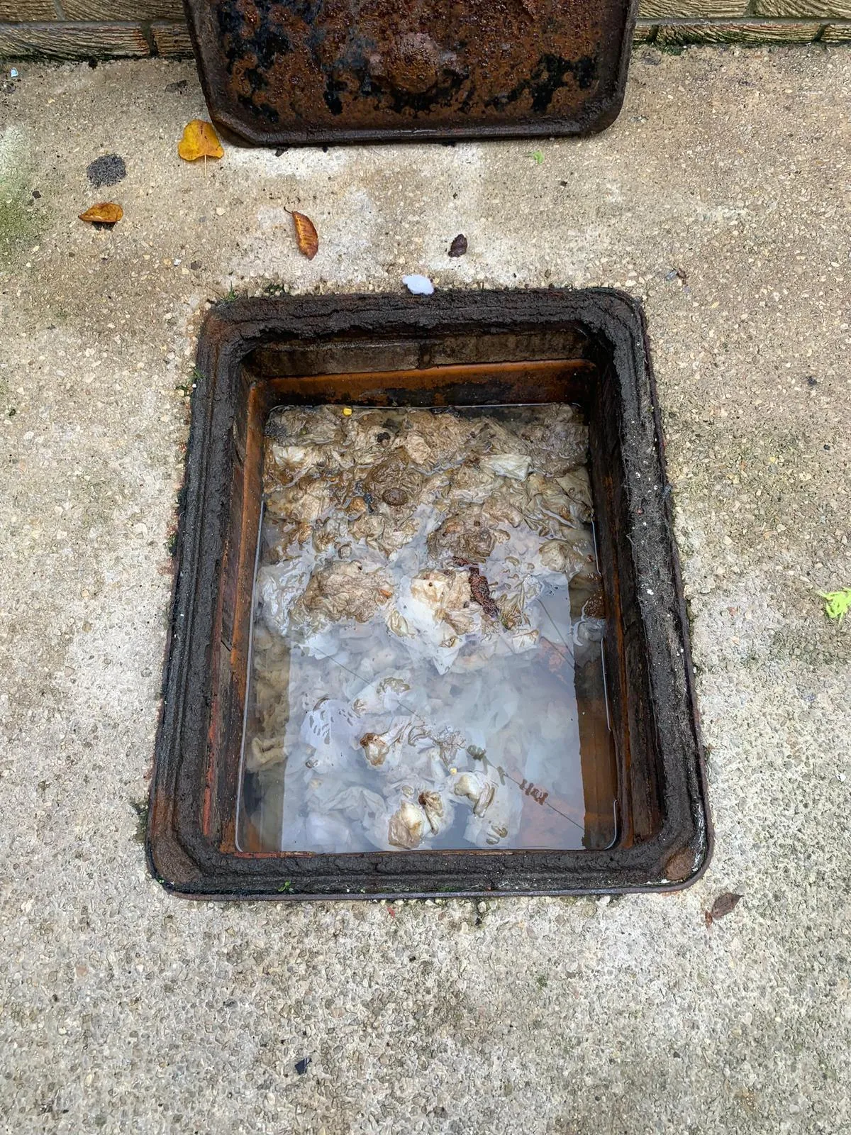 A blocked sewer drain manhole overflowing with water and wet wipes, requiring professional unblocking in Durham.