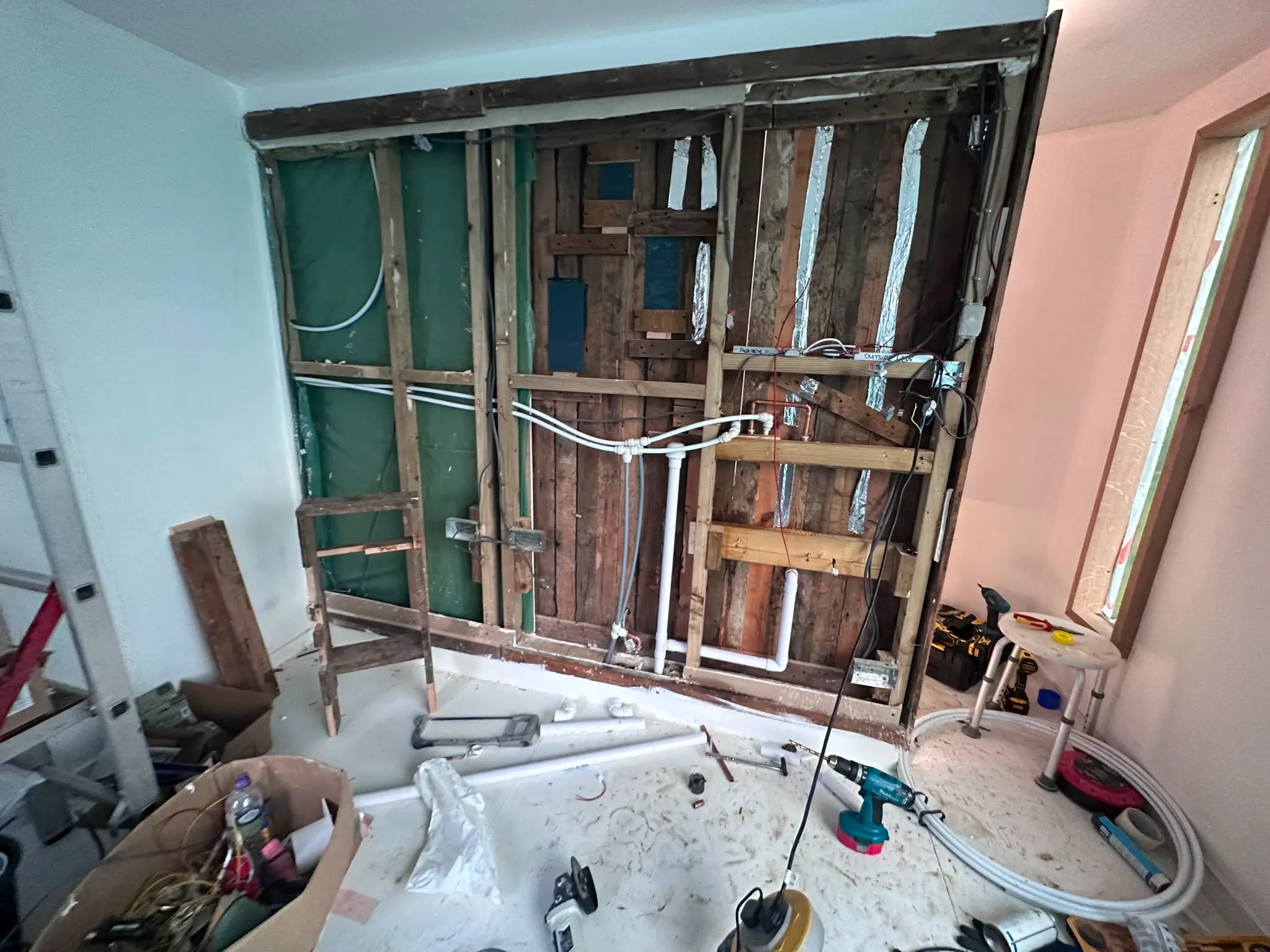 Exposed stud wall showing first-fix plumbing pipework installation in a residential renovation.
