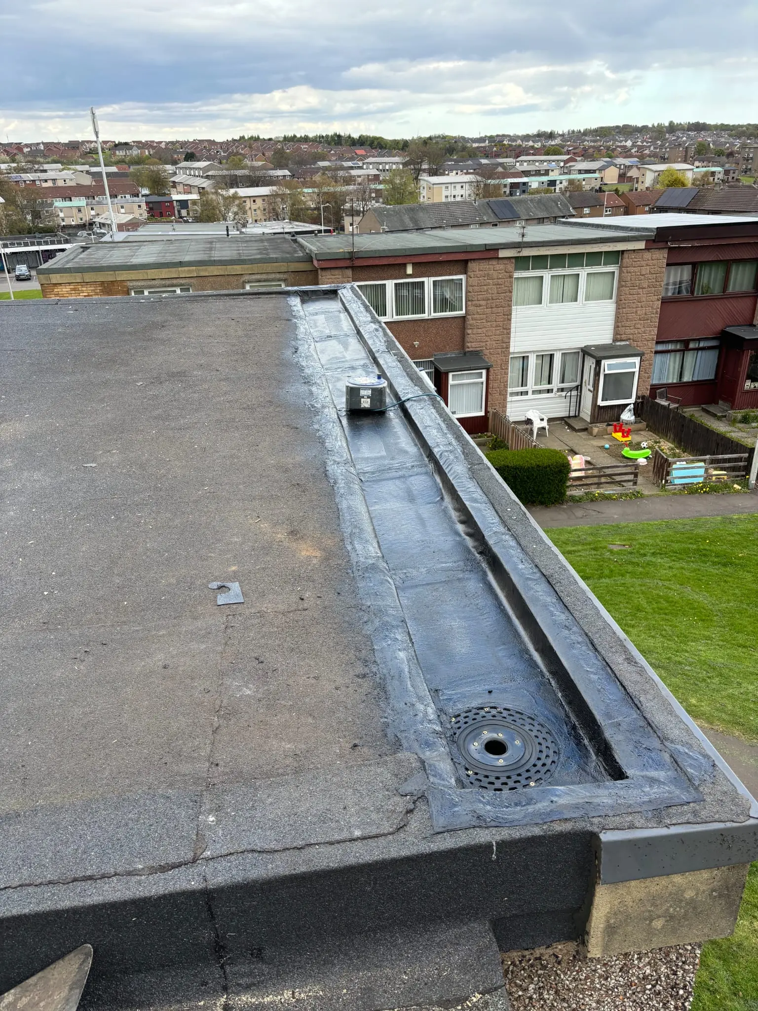 A flat roof with a repaired drainage channel in a residential area, likely in Fife or a surrounding region