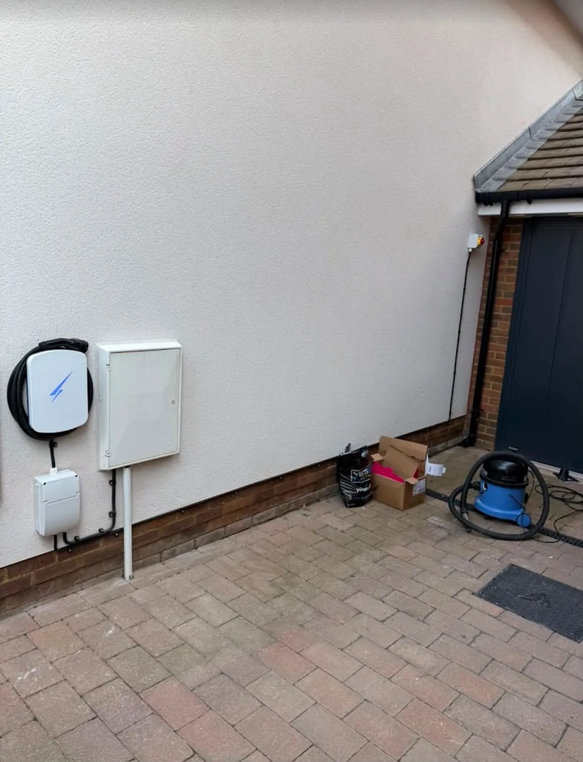 Domestic EV charger installation on an exterior brick and render driveway wall by Sussex Brown Sparks