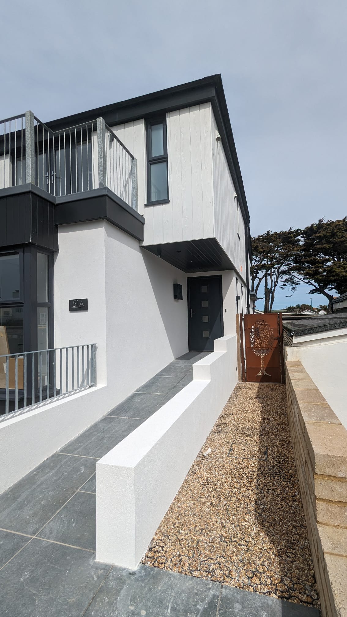 Modern house with a fresh white rendered finish and grey detailing, completed by Portslade Plastering.