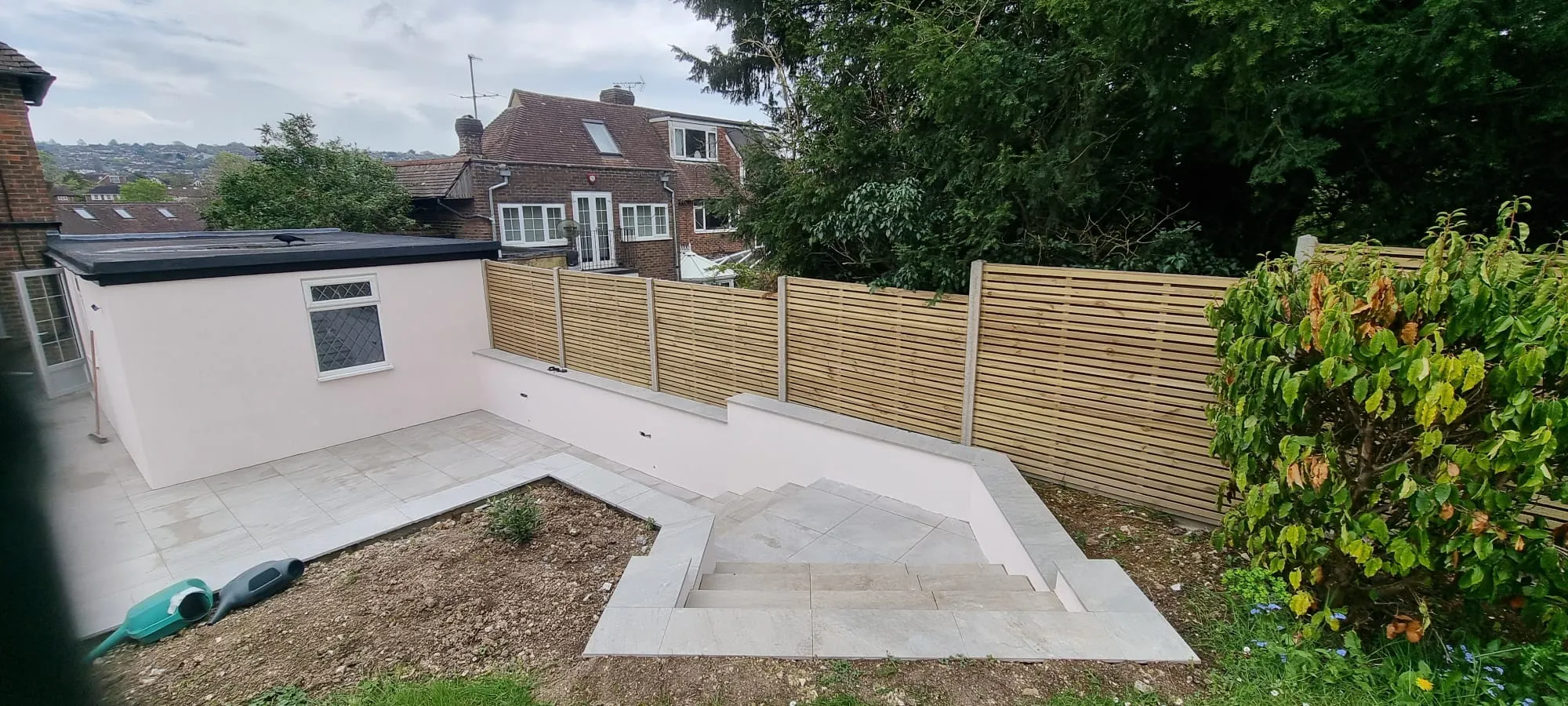 Modern garden renovation showing smooth external rendering and new patio tiling in Sussex.