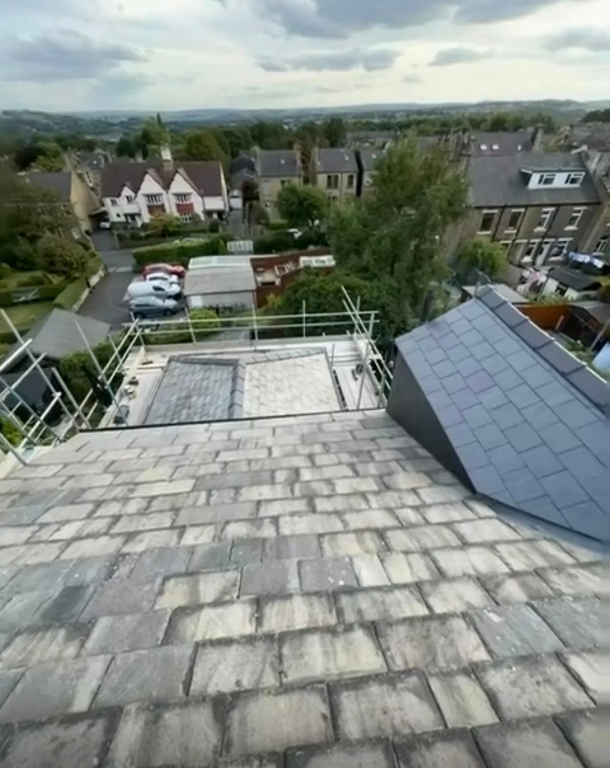 A completed stone slate roof installation with scaffolding in Holmfirth, West Yorkshire