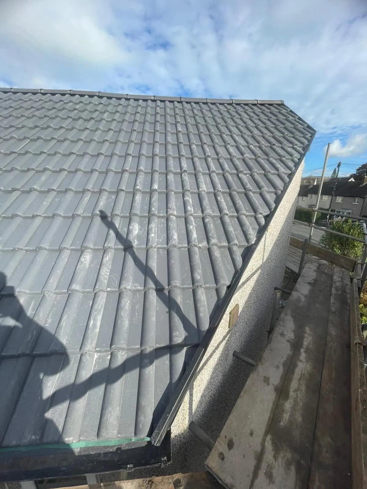 New pitched roof installation in Lancashire featuring grey concrete tiles and professional scaffolding setup.
