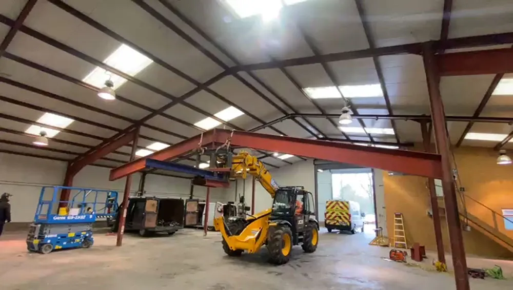 Telehandler lifting a structural steel beam during a construction project in Southampton