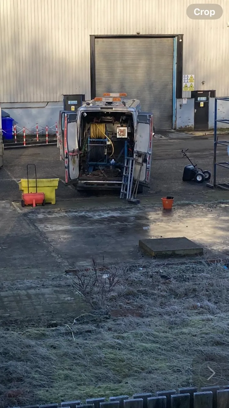 Back of a KO Drainage van with open doors, revealing yellow high-pressure water jetting hoses and equipment for drain cleaning.