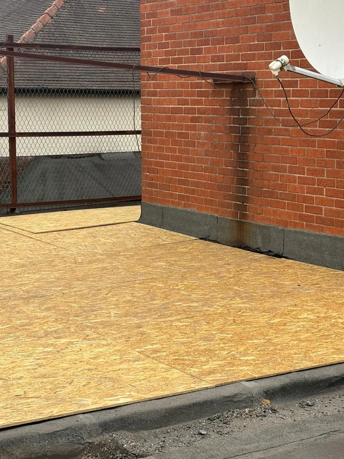 OSB boards laid on a flat roof next to a brick wall, part of flat roof installation