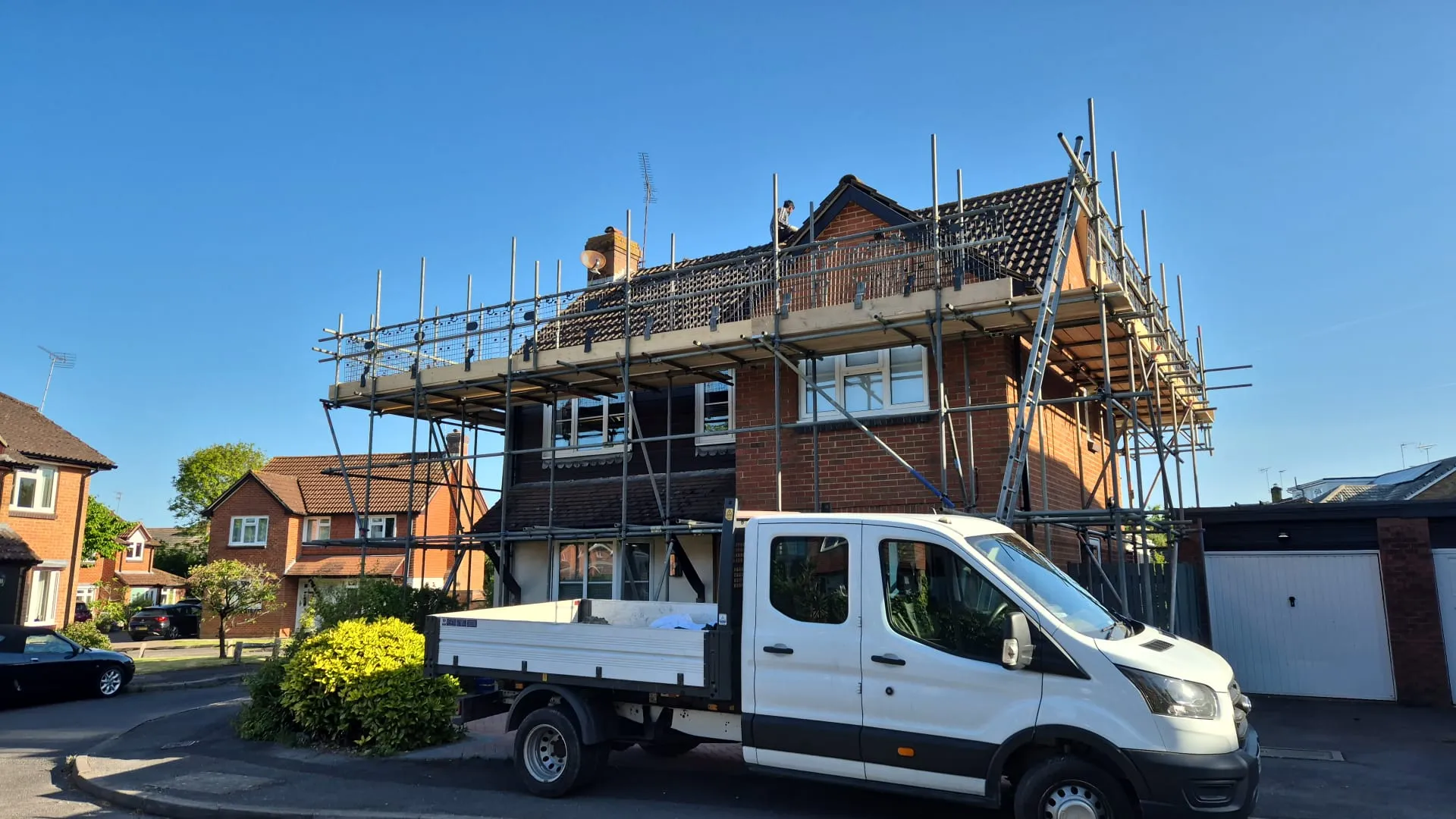 Expert roofing services in progress with a work van and scaffolding at a house in Hampshire.