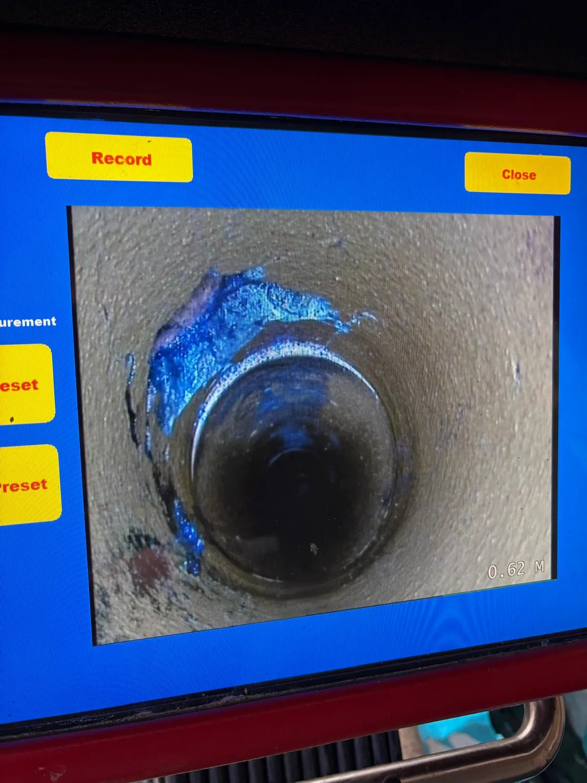 A CCTV camera inspection of a drain showing the interior of the pipe on a screen
