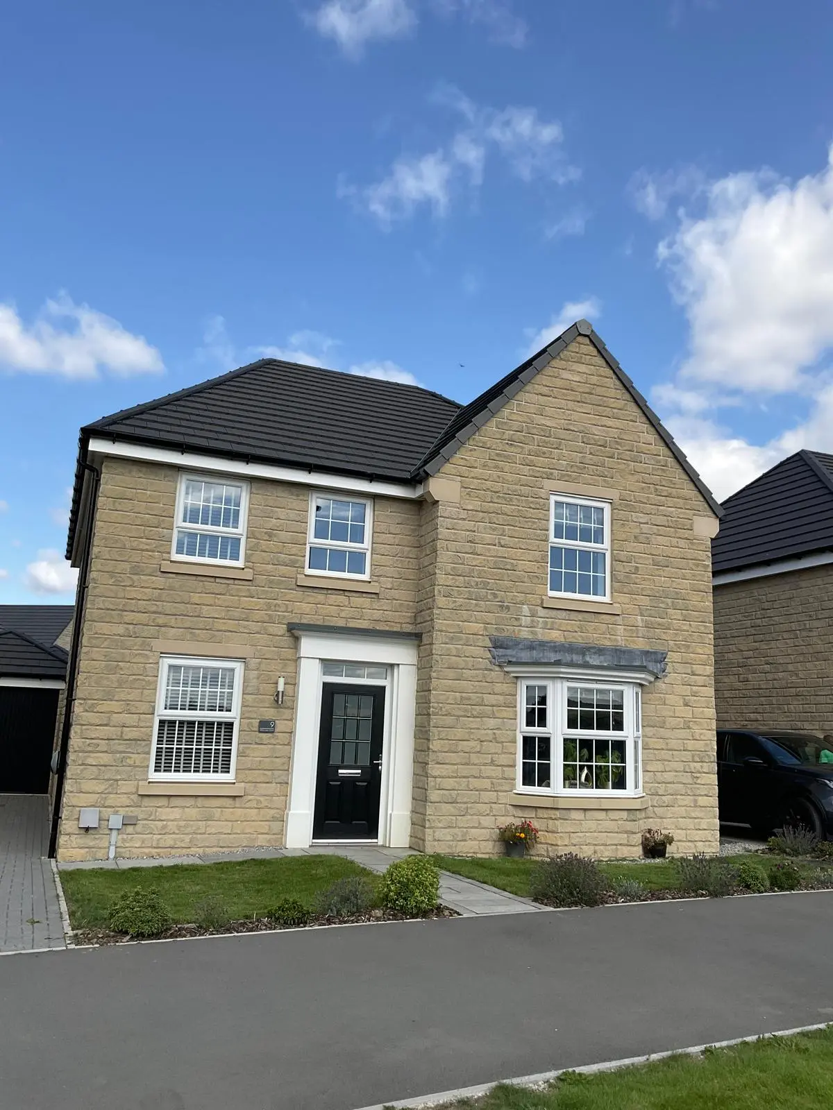 A modern stone house featuring a professionally installed dark grey tiled pitched roof
