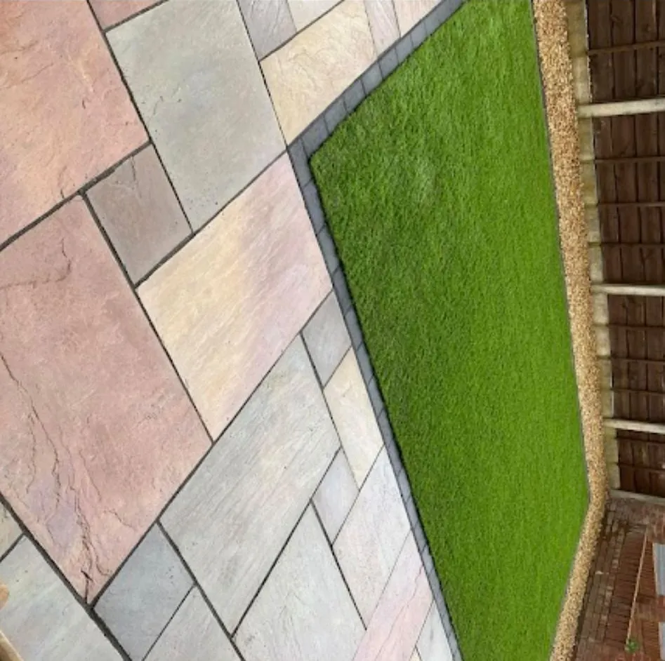 Professionally installed Indian sandstone patio and artificial lawn in a residential garden.