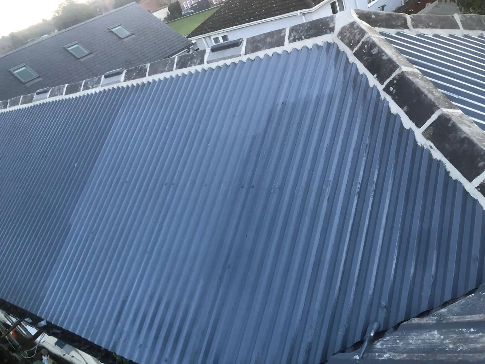Overhead view of a grey corrugated metal roof, representing garage or extension roofing work.