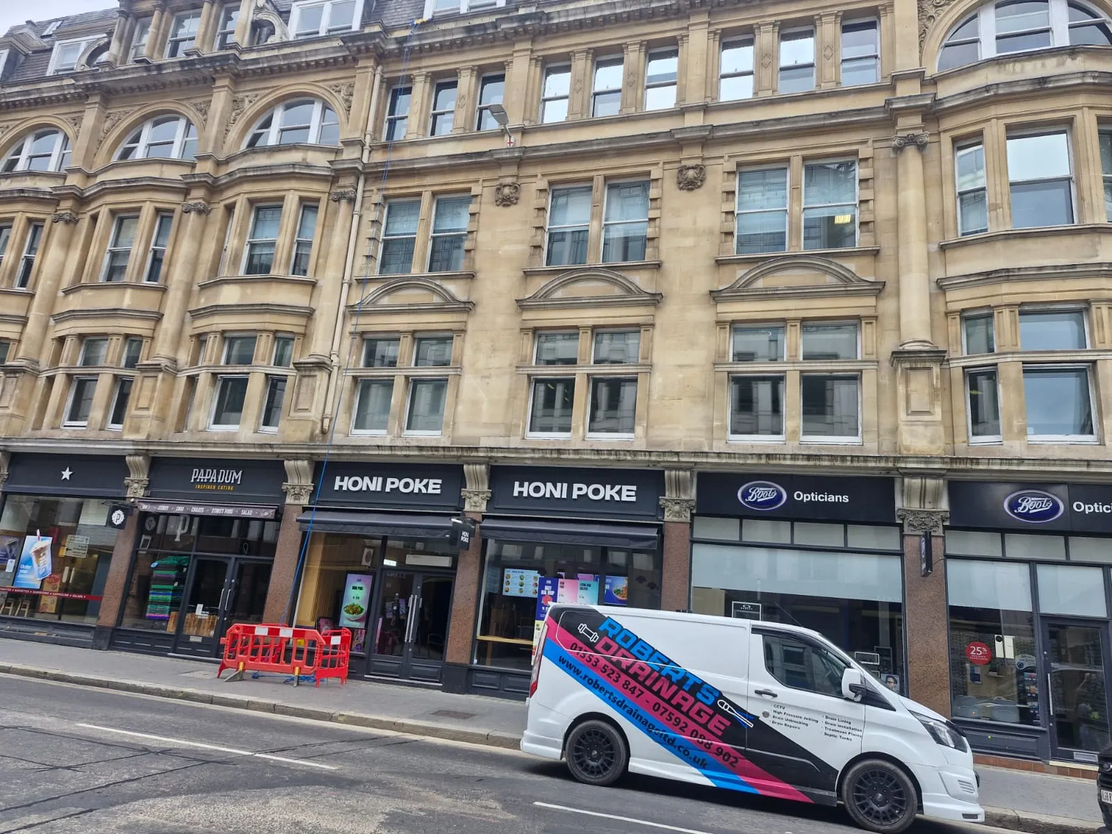 Roberts Drainage Ltd van parked outside commercial shops for drainage maintenance.