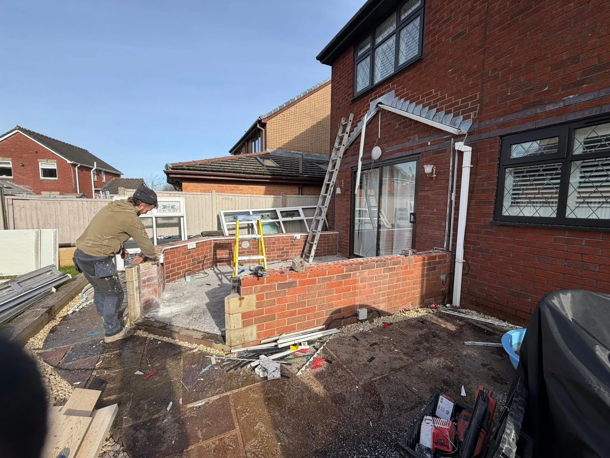 A builder from Lancashire Roofing Specialist constructing a brick base for a new house extension in Blackburn.