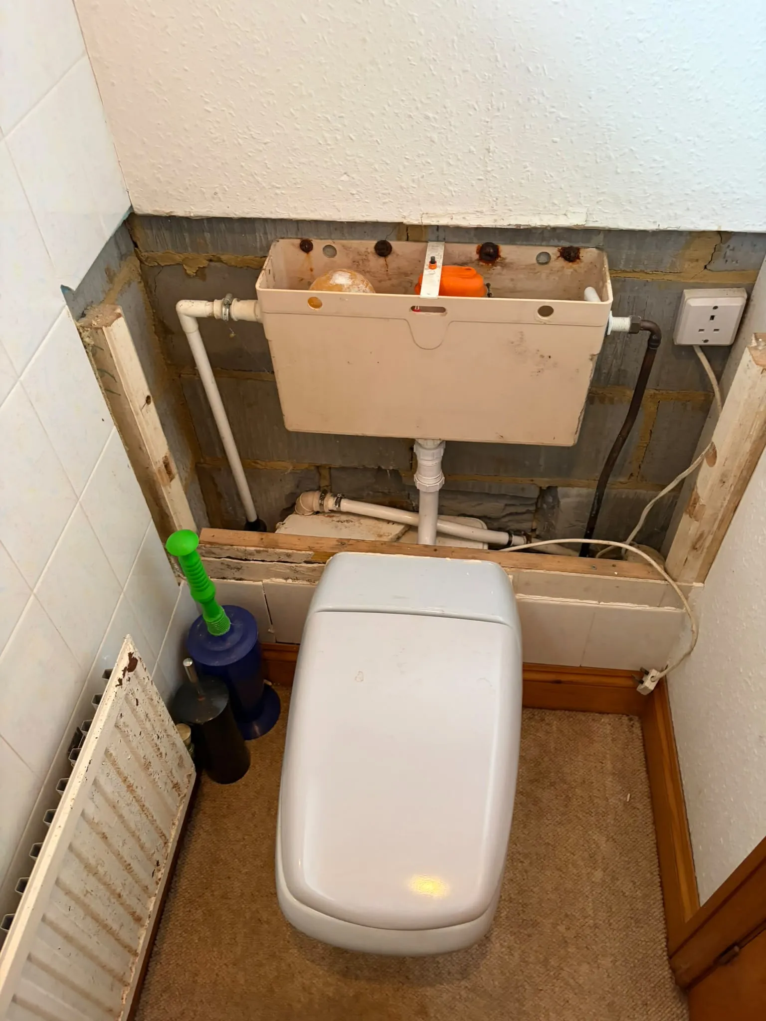 Concealed toilet cistern and internal soil pipework exposed during emergency toilet unblocking and repair in Slough