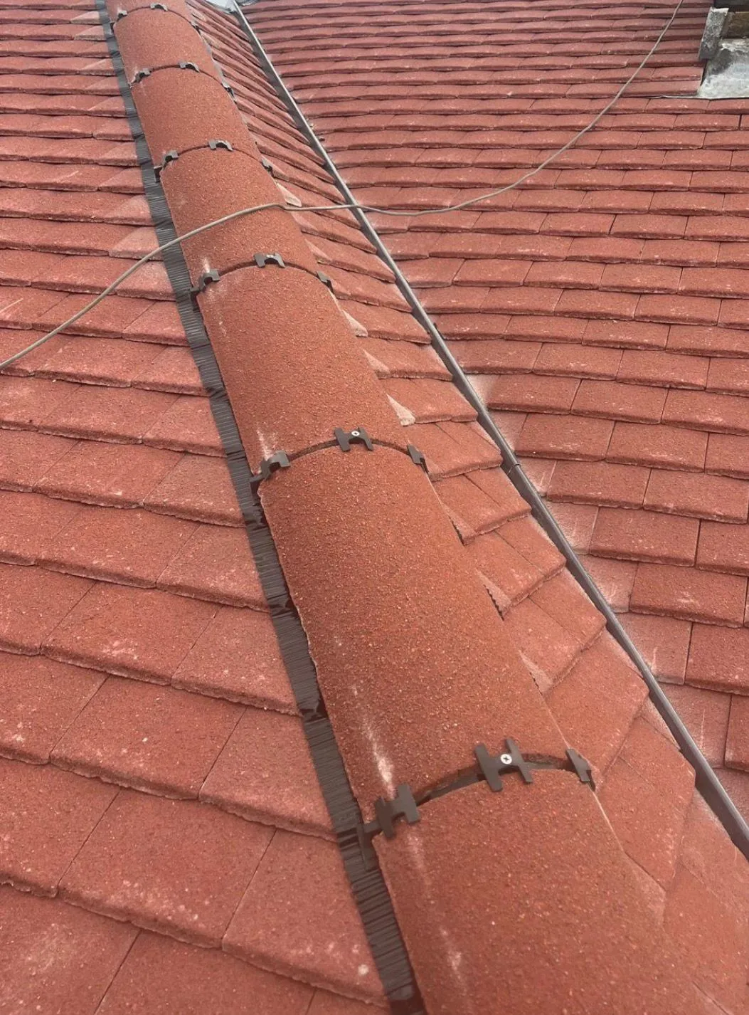 Close-up of a newly installed dry hip system and red roof tiles on a residential property.
