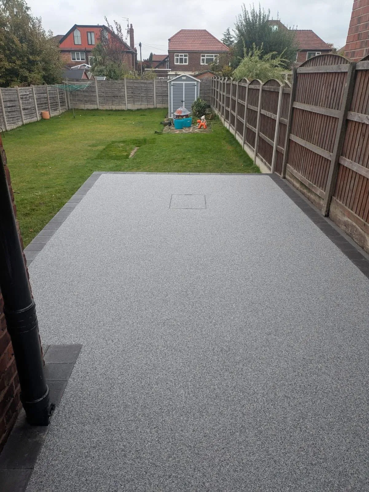 A modern grey resin bound patio with a decorative block paving border in a Canterbury garden.