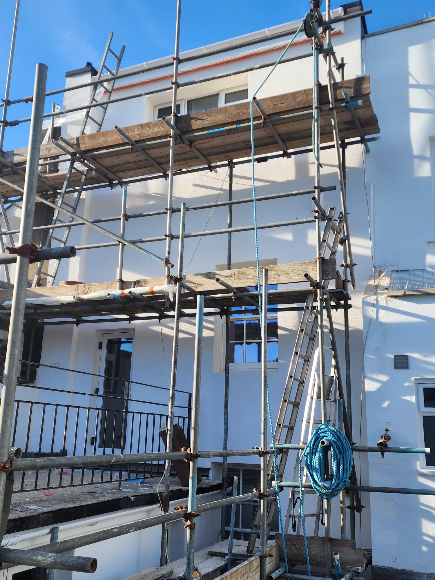 Metal scaffolding in place for external rendering work on a white building.