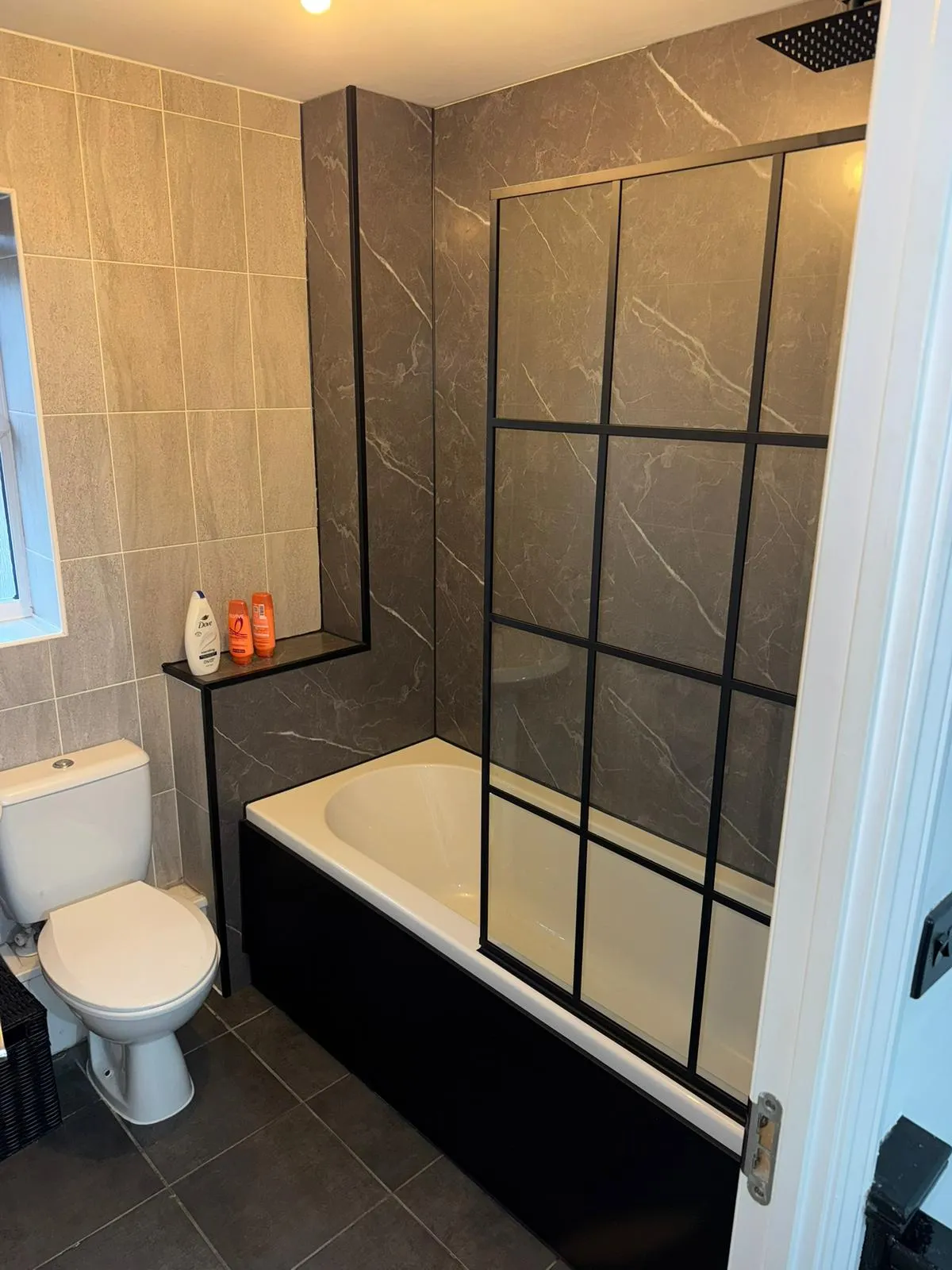 Modern bathroom installation with a crittall-style shower screen and marble-effect tiling by Redorr Heating & Cooling Services Ltd.