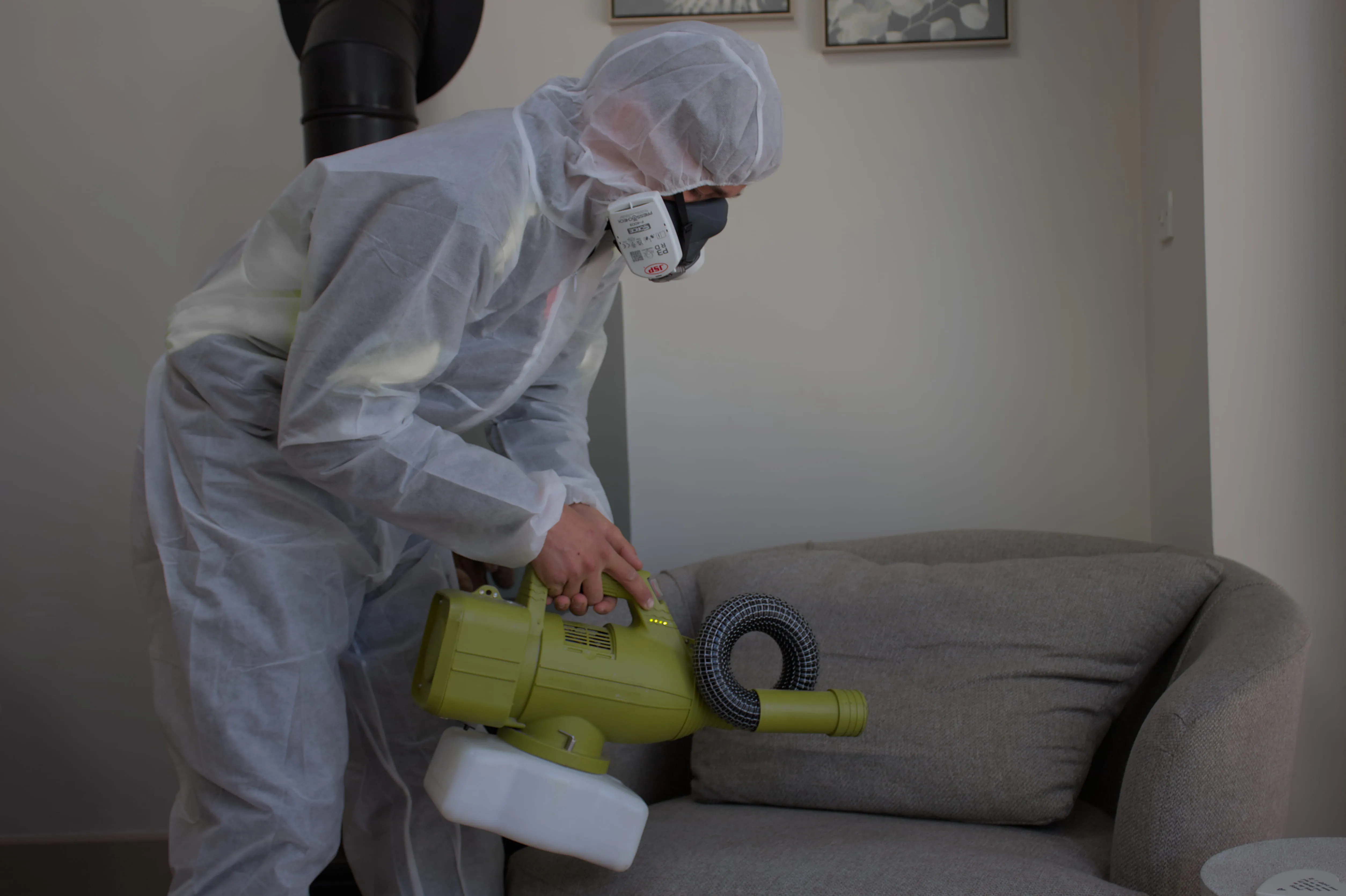 A professional pest control technician performing fumigation and insect treatment on a sofa in Harrogate.