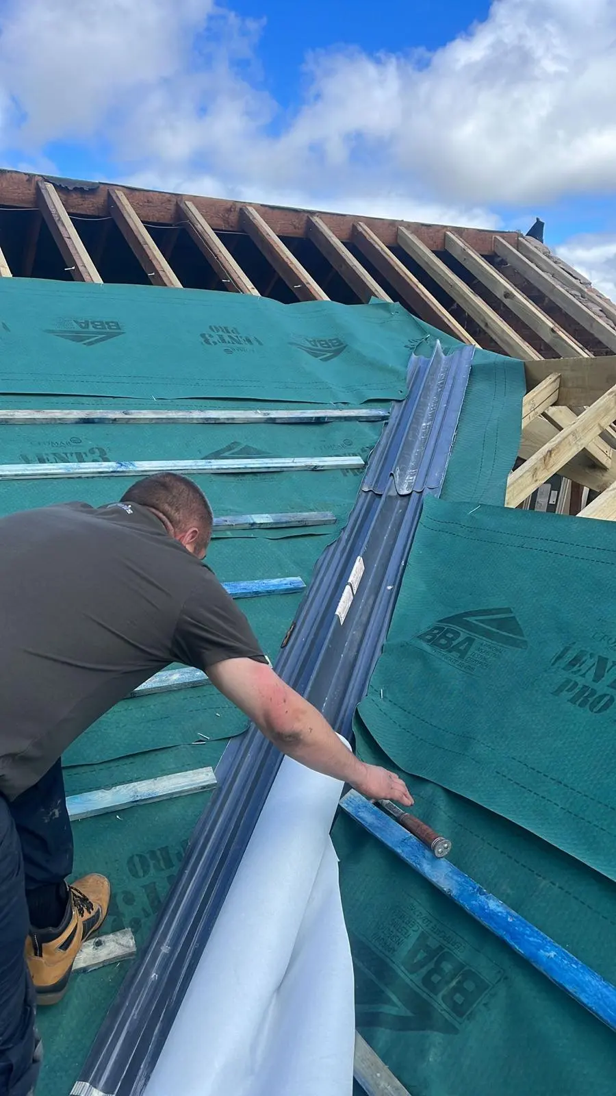 Expert roofer installing a new roof valley system and breathable membrane during a roof replacement in Ellesmere Port