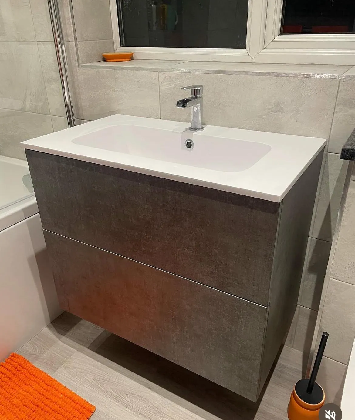 Modern grey wall-hung bathroom vanity unit with integrated basin and chrome mixer tap.