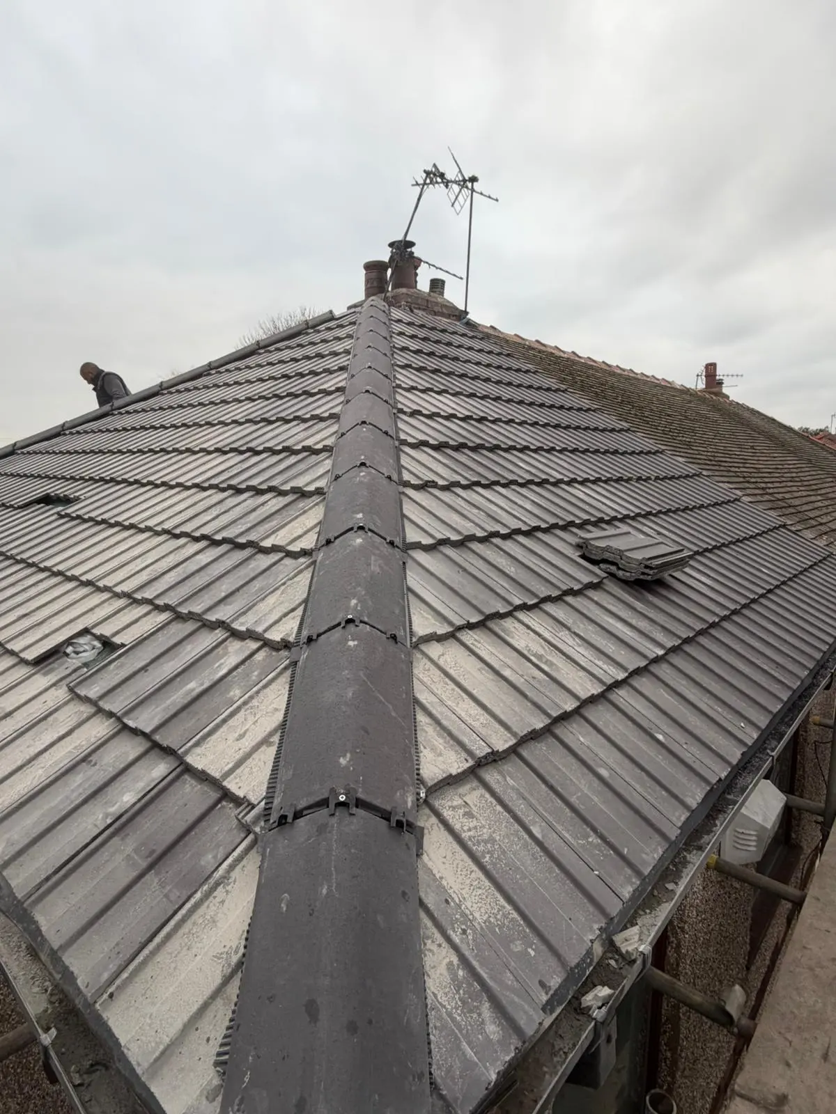 A close-up view of a newly installed dry ridge system on a tiled roof.