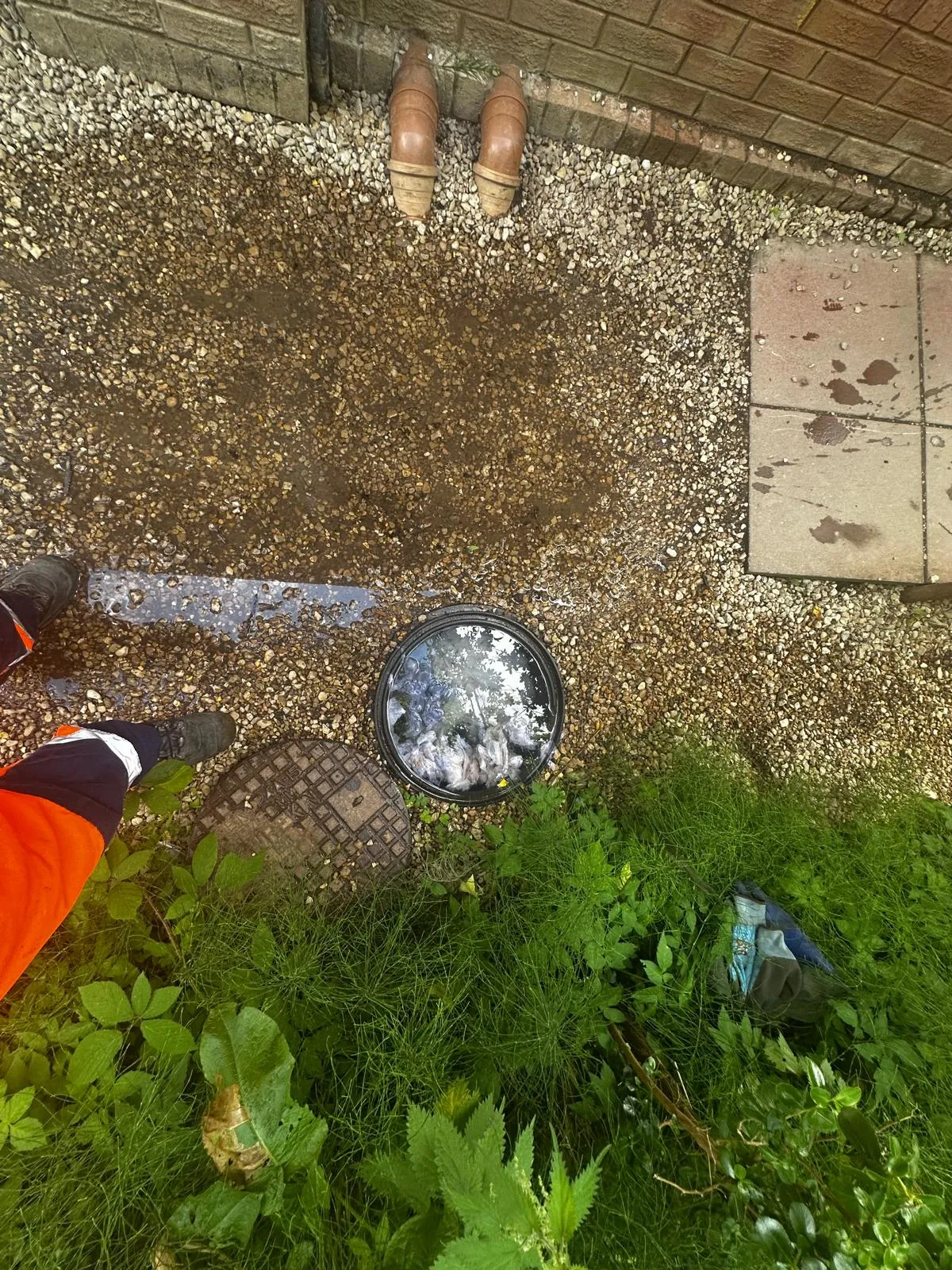 A picture of a drainage technician attending to an overflowing outdoor drain.