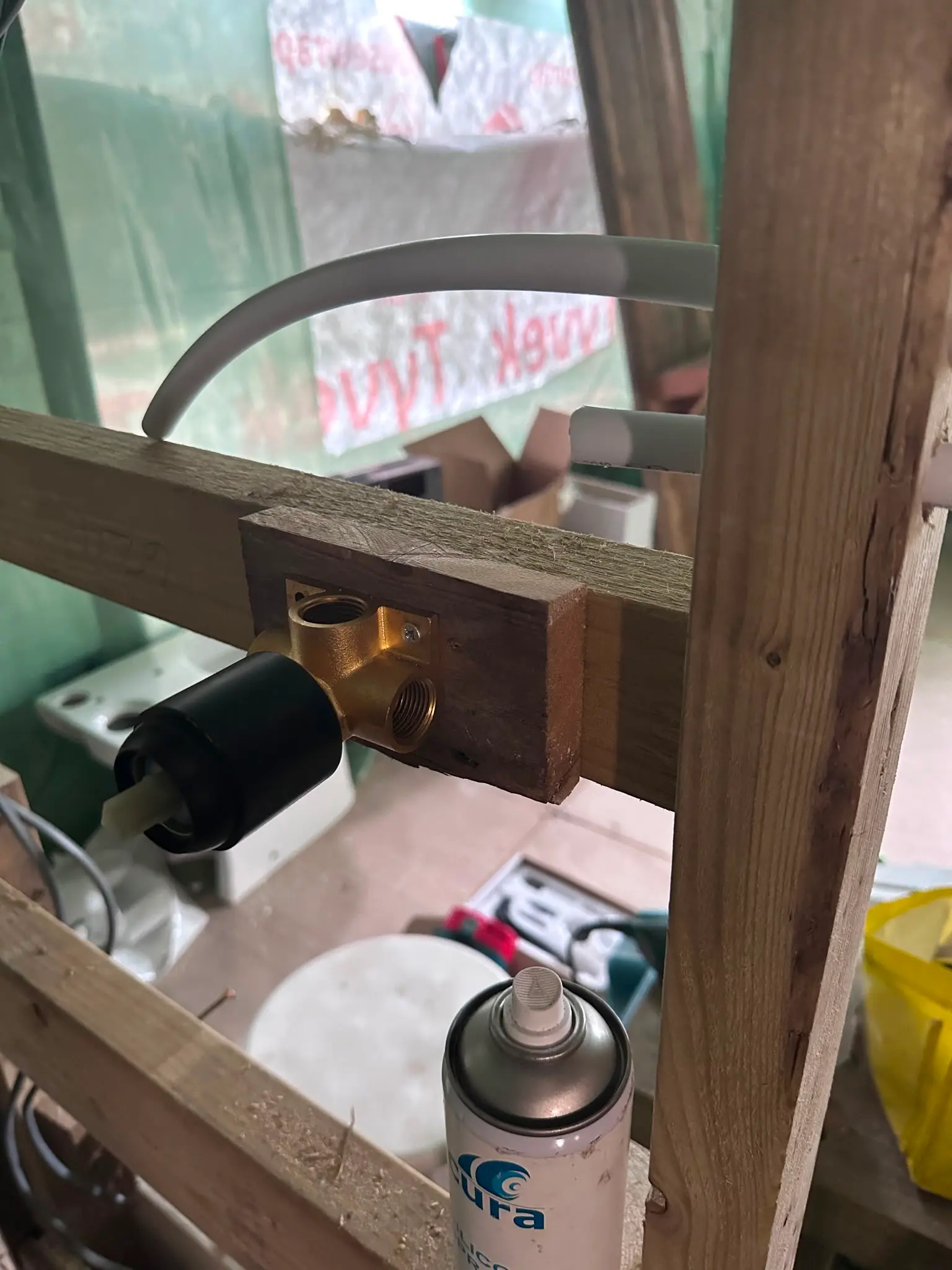 A close up picture of a brass shower valve fixed to a wooden frame