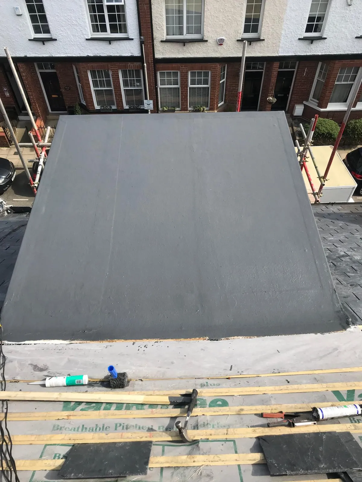 DSR Roofing York installing a durable grey GRP fibreglass flat roof and preparing a pitched roof with slate tiles on a residential property in York.