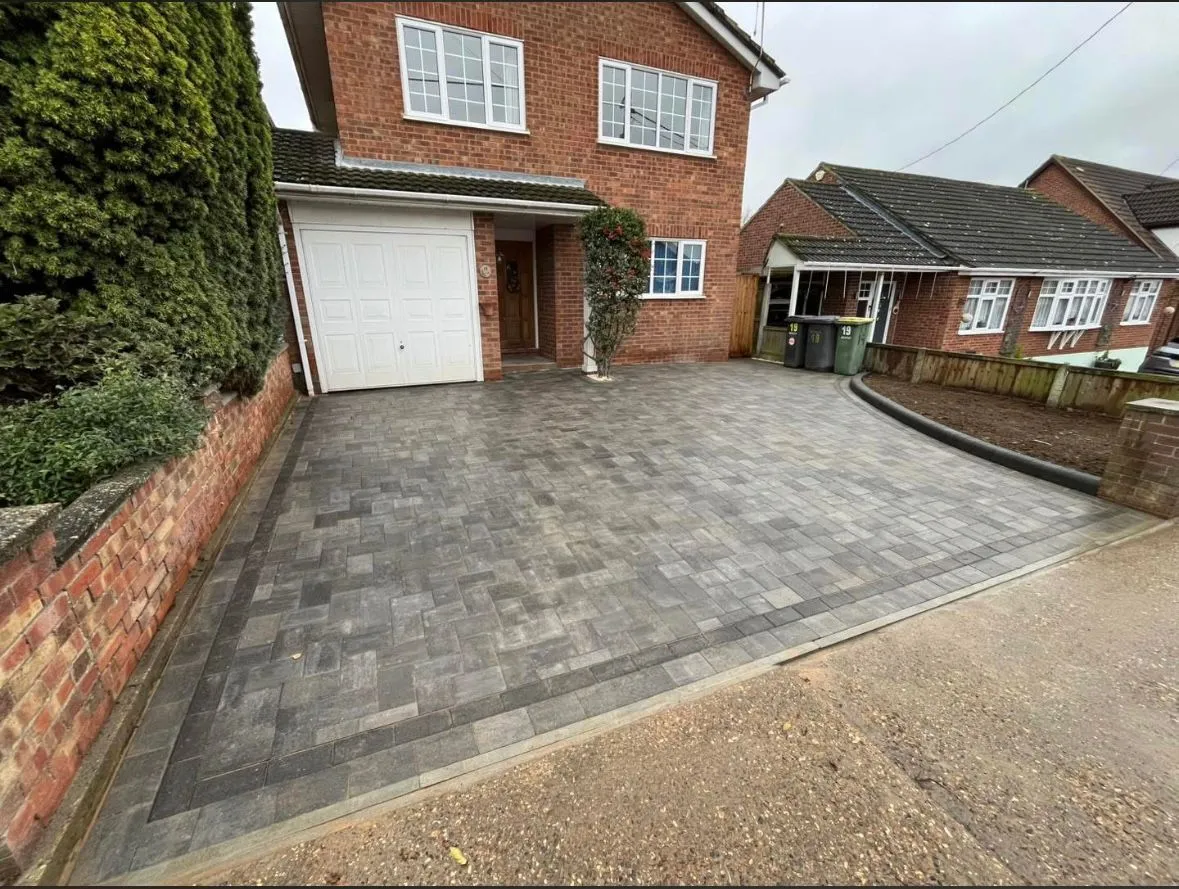 Newly installed grey block paving driveway in front of a residential home