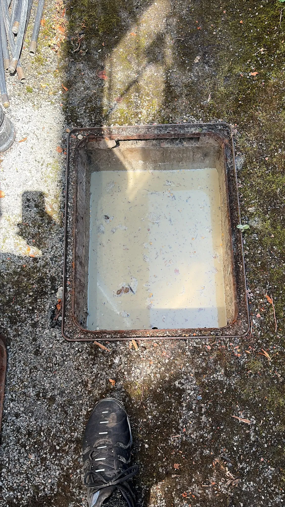 Blocked inspection chamber filled with standing wastewater awaiting emergency drain unblocking in Slough