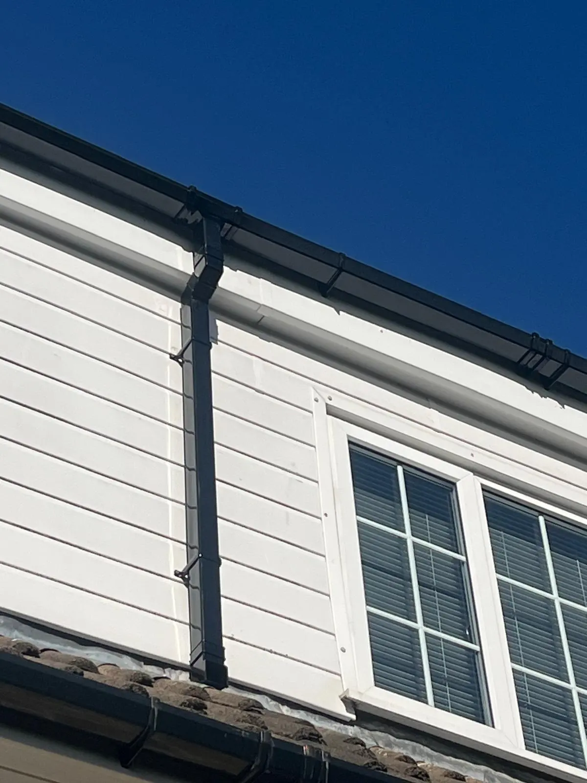 Professional black uPVC guttering and downpipe installation on a residential property