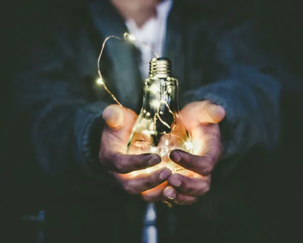 Hands holding a glowing lightbulb symbolising energy efficiency concepts for domestic properties