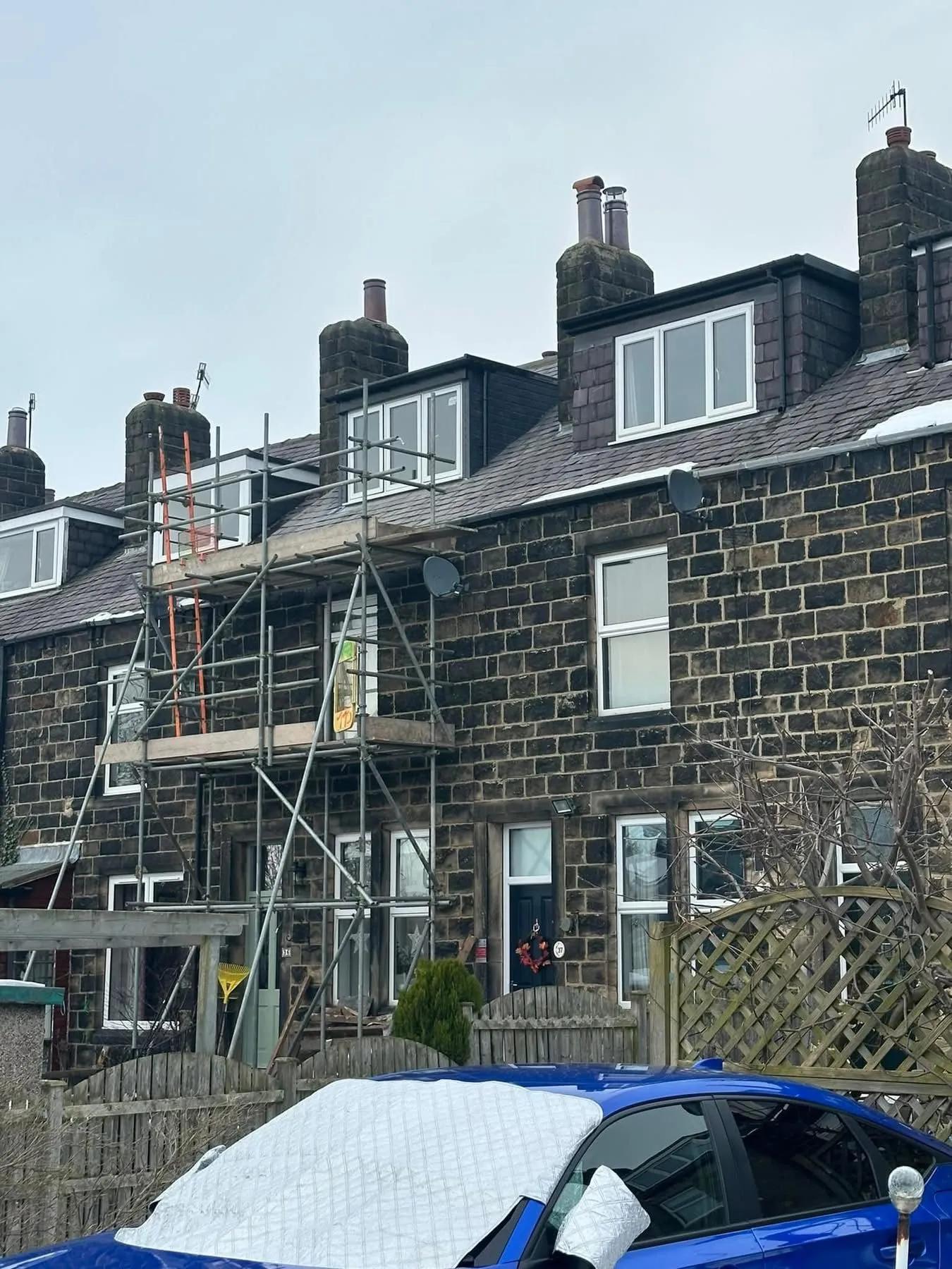 Scaffolding installed on a stone terraced house in Leeds for roofing services.
