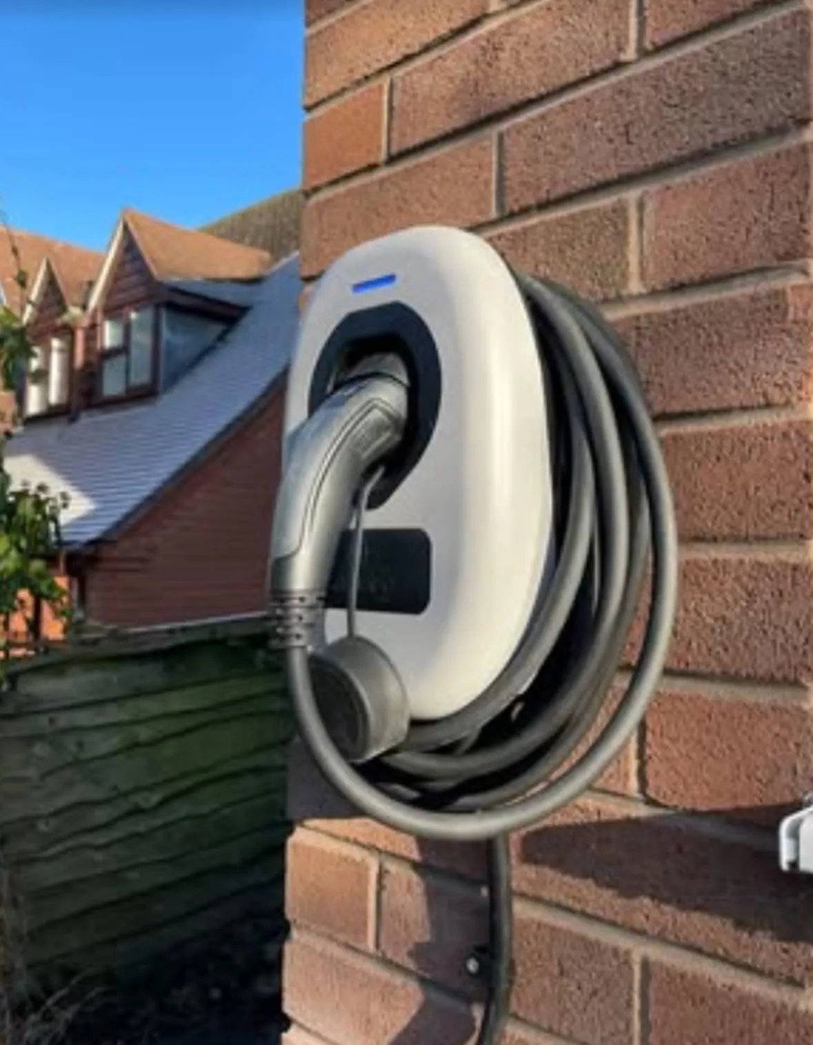 Domestic smart EV charger installed on an exterior brick wall of a home
