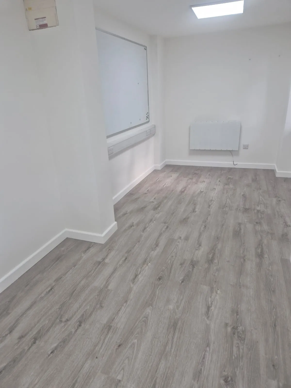 Interior view of a modern, empty commercial office after refurbishment, featuring light grey flooring and white walls.