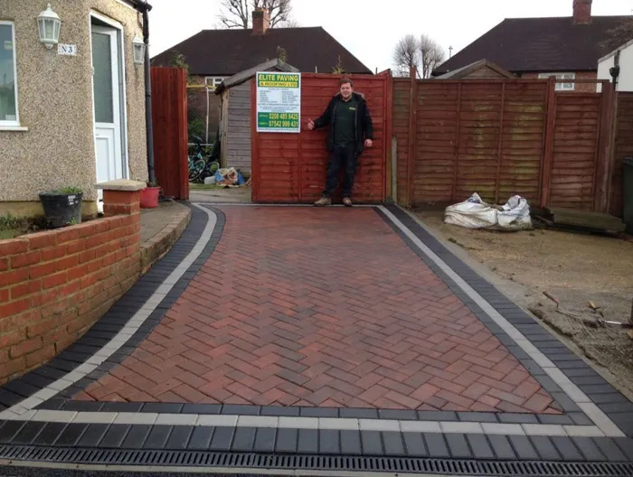 Newly laid red block paved driveway by Elite Paving and Roofing LTD, showcasing herringbone pattern, contrasting borders, and a modern drainage system.