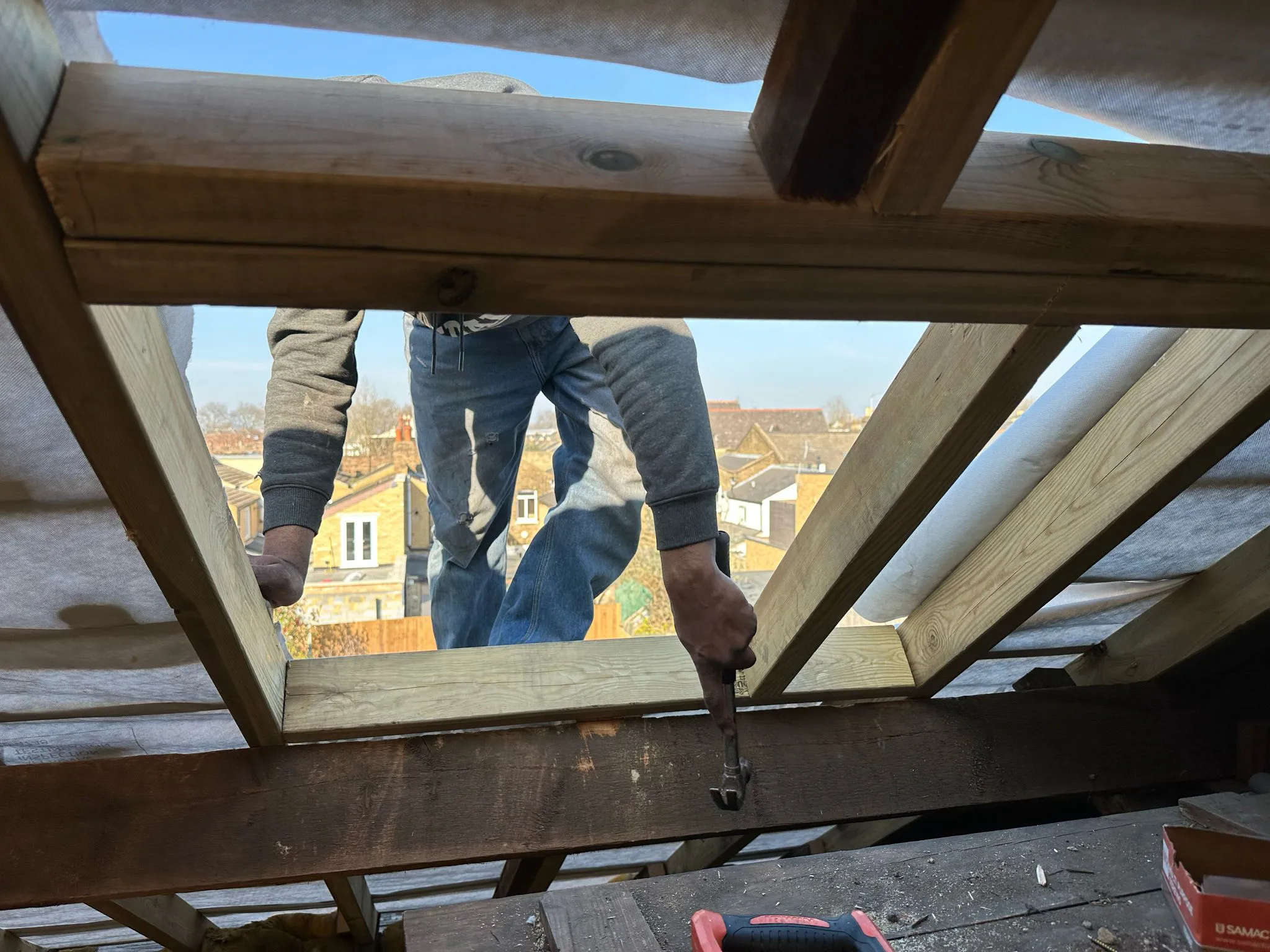 Roofing specialist fitting new timber rafters and framing on a pitched roof repair