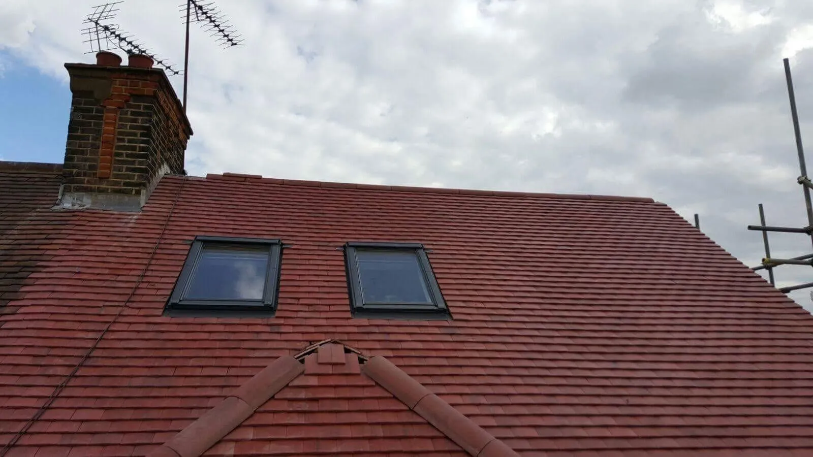 New red tile roof installation with skylights and chimney by Firmus Roofing & Building