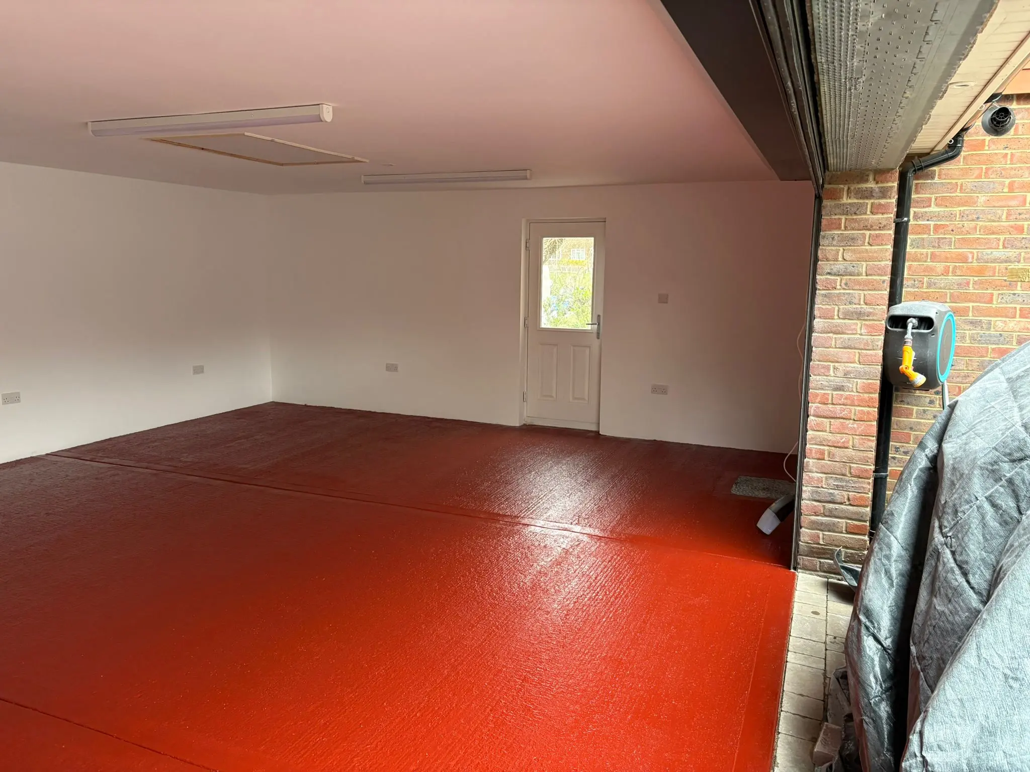 Empty garage interior with fresh white walls and a glossy red floor