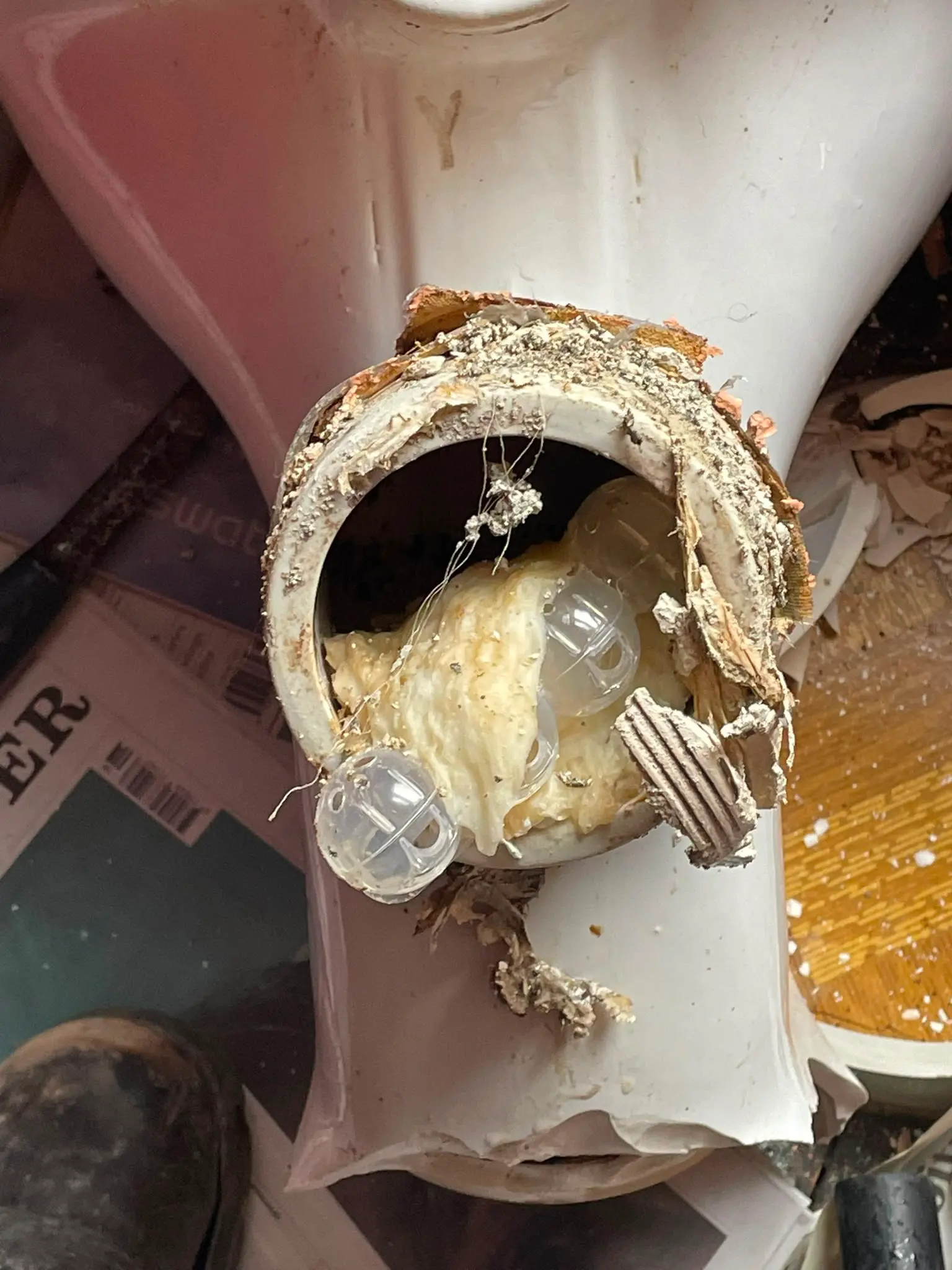 A severely blocked and broken toilet waste pipe showing trapped wipes and plastic objects