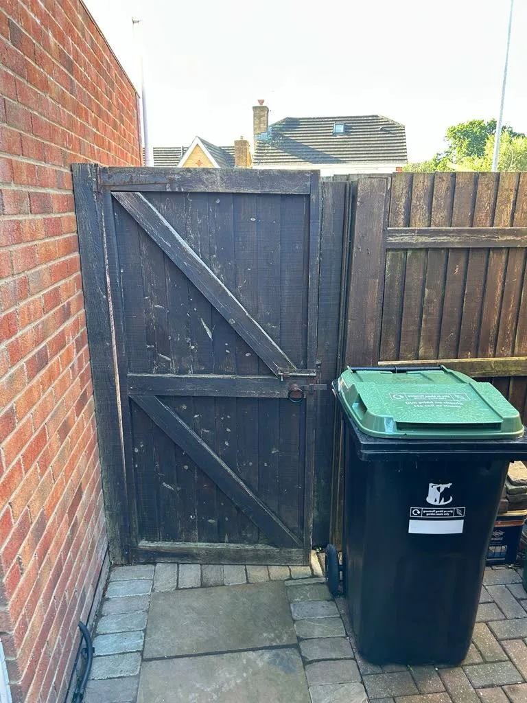 Old timber garden side gate requiring replacement alongside residential boundary fencing